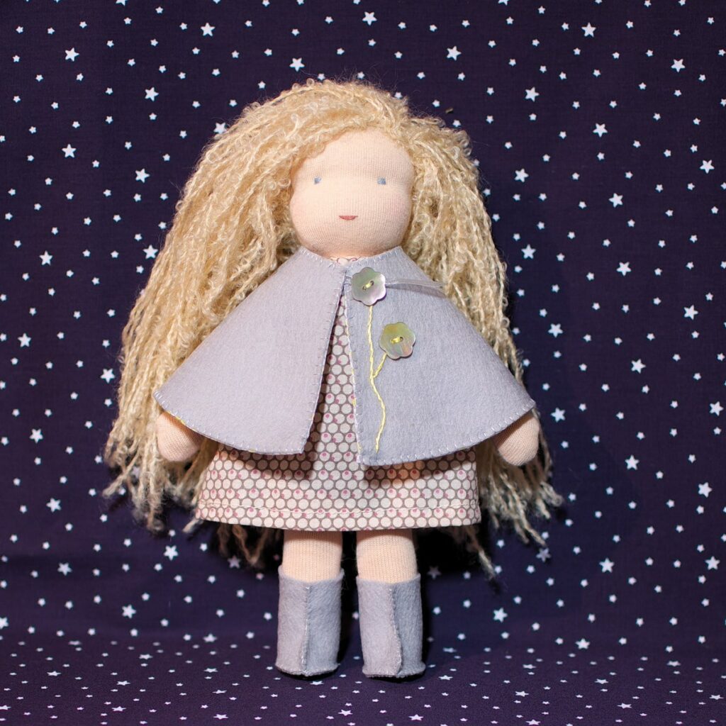 La cape et les bottes sont à confectionner à partir de feutrine de laine, popeline, ruban et jolis boutons, un patron de couture pour poupées.