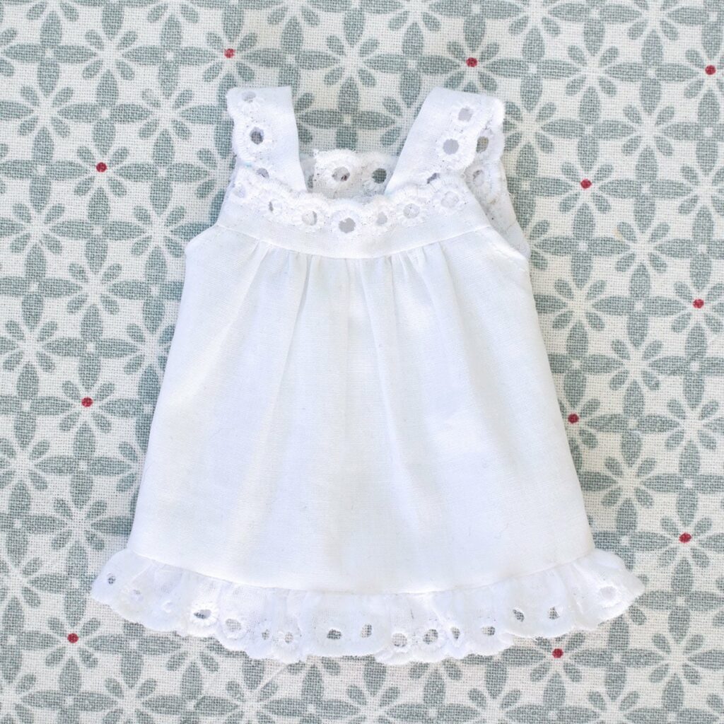 La chemise de nuit en popeline et broderie anglaise est à confectionner pour les poupées Waldorf de 23cm grâce au patron de couture pour poupées